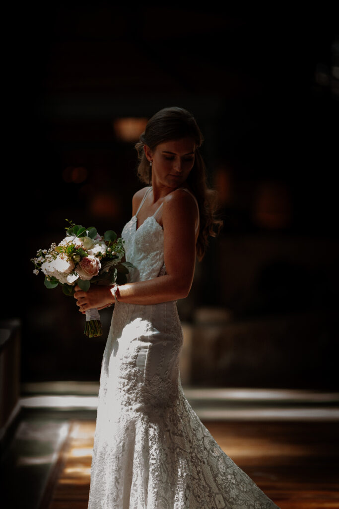 Bride in wedding dress in Spain looking down over her shoulder holding wedding flowers